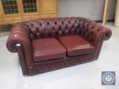A red leather two seater Chesterfield settee