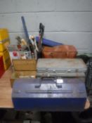 A leather bag, three metal cases and a bucket containing vintage hand tools, copper blow lamps,