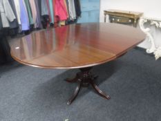 A circular mahogany extending pedestal dining table