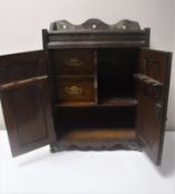 A Victorian oak double door smoker's cabinet with carved panel doors