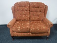 A two-seater wingback settee upholstered in a floral print