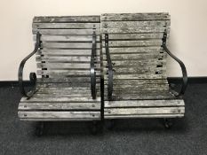A pair of wrought iron and teak scroll arm garden armchairs