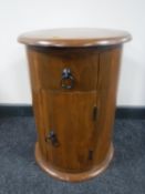 A cylindrical mango wood bedside cabinet