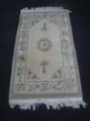 A fringed floral Chinese embossed rug on cream ground