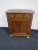 A continental mahogany cabinet fitted a drawer on bun feet