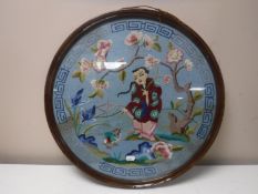 A circular mahogany framed oriental needlework panel