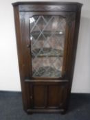 A carved oak leaded glass door corner display cabinet