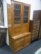 A Jaycee oak cocktail bookcase fitted cupboards and drawers beneath