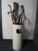 A waste paper bin containing walking sticks, parasols,