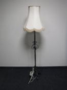 A wrought iron standard lamp with shade