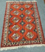 A Caucasian design rug on red ground,