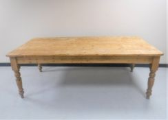 A large pine farmhouse kitchen table together with a set of eight pine farmhouse chairs.