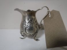 A miniature embossed silver milk jug