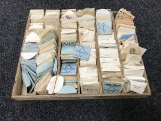 A wooden tray containing a collection of vintage watchmaker's crystals
