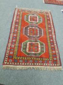 A Caucasian design rug on red ground,
