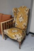 An early 20th century continental oak wingback armchair on cabriole legs