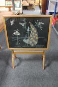 An early 20th century folding oak needlework table screen depicting a peacock