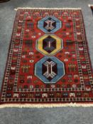 A Caucasian fringed rug on red ground,
