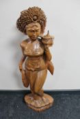 A carved hardwood eastern figure of a lady carrying a pot