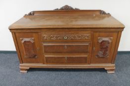 A 20th century carved oak sideboard with walnut panelled doors