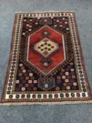 A Caucasian fringed rug on red ground, with floral border,