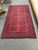 An Eastern wool rug on red ground,