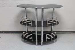 A contemporary black glass and metal three tier bar