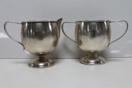 A white metal sugar basin and milk jug,