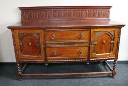 A late Victorian carved oak rail back sideboard on barley twist legs