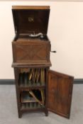 An oak cased HMV gramophone on cabinet containing a quantity of 78's