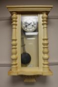 An early twentieth century painted wall clock with enamelled dial and pendulum