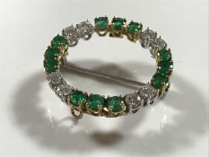An 18ct gold diamond and emerald circular brooch, approximately 1.5ct, 5.2g.