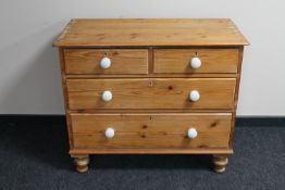 An antique pine four drawer chest with white porcelain handles