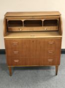 A mid twentieth century teak barrel fronted bureau