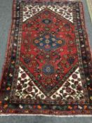 A fringed Persian rug of geometric design on red ground