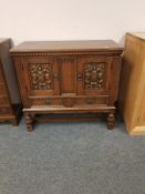 A carved oak double door low cupboard,