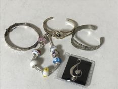 A bag containing four silver bracelets together with a silver brooch