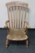 An antique pine rail back kitchen armchair