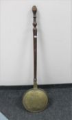 An antique brass and copper bed warming pan