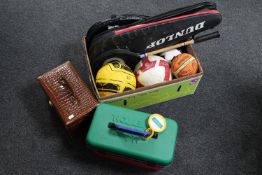 A box of sports rackets and balls,