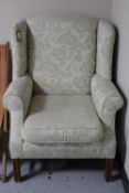 A wingback armchair upholstered in a cream floral fabric