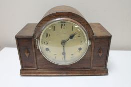 A 1930's oak cased mantel clock with silvered dial