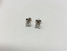 A pair of solitaire diamond earrings in platinum.