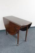 An antique mahogany drop leaf table on club feet