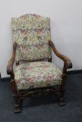 An early 20th century carved oak scroll arm armchair in tapestry fabric