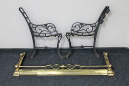 An antique brass extending fire curb and a pair of cast iron garden bench ends