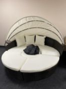 A rattan day-bed with cushions and canopy