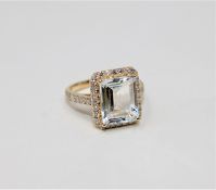 A 14ct gold aquamarine and diamond cluster ring, the pale blue emerald-cut aquamarine weighing 3.