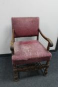 An early 20th century carved oak arm chair in purple fabric