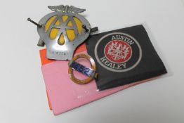 A box containing vintage AA badge, two cloth Austin Healey badges,